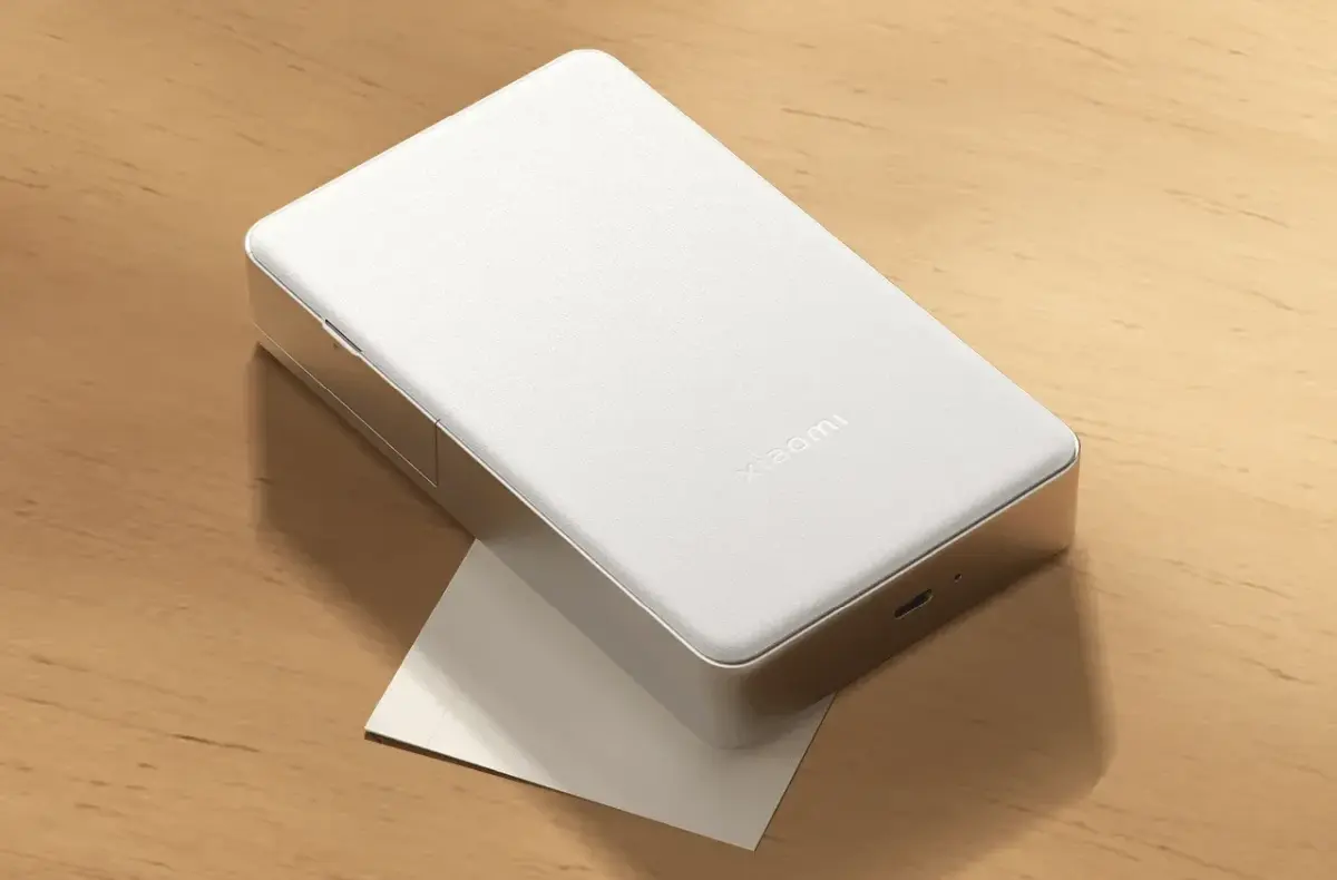 Xiaomi Portable Photo Printer Pro na stole s papirkem pod sebou