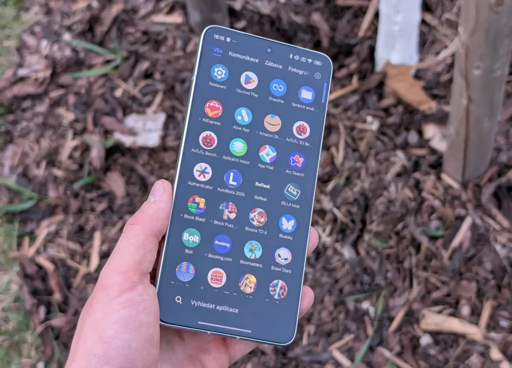 poco f7 pro v ruce displej nad drevem